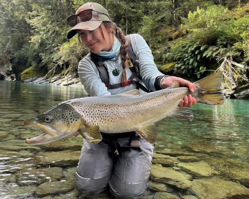 Women holding a big trout in the river 