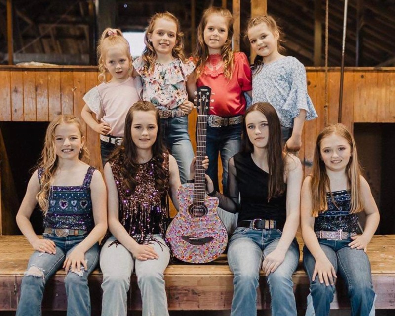 Halton Hart Family Band members smiling together in a group with a guitar in the middle 