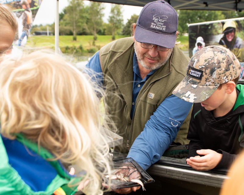 Fish & Game ranger showing children baby fish at On the Fly River Festival in Gore Southland 