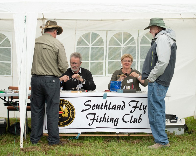 Southland Fly Fishing Club members doing a fly tying demo for two men. 