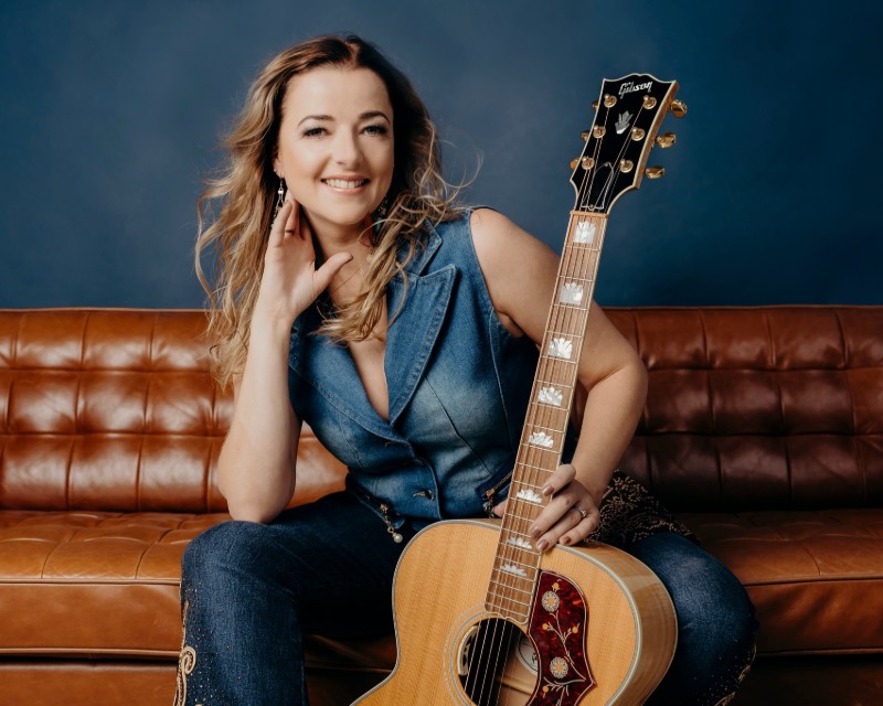 Kayla Mahon holding a guitar smiling 